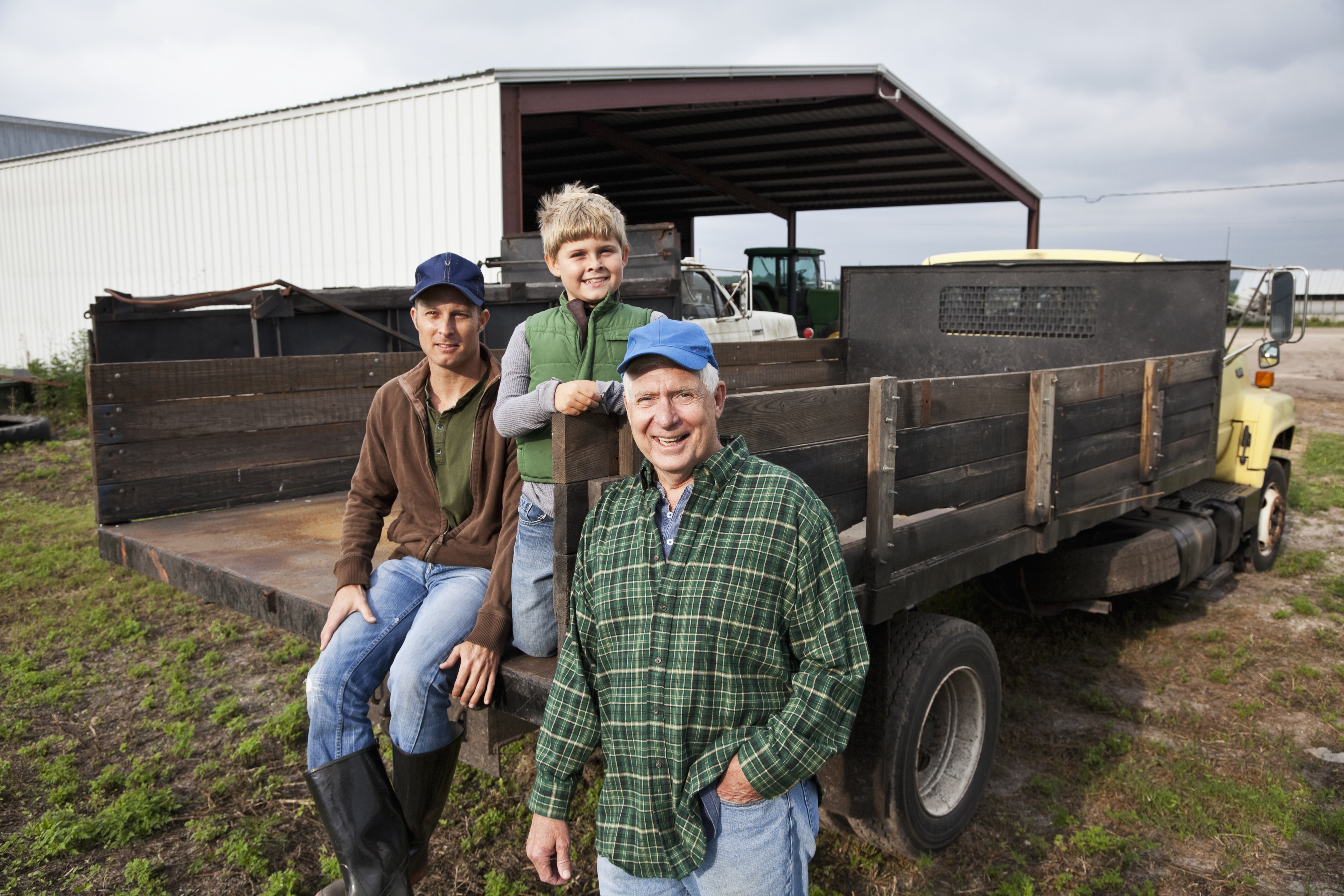 Farmers and young boy around the back of a truck