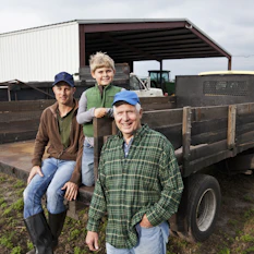 Farmers and young boy around the back of a truck