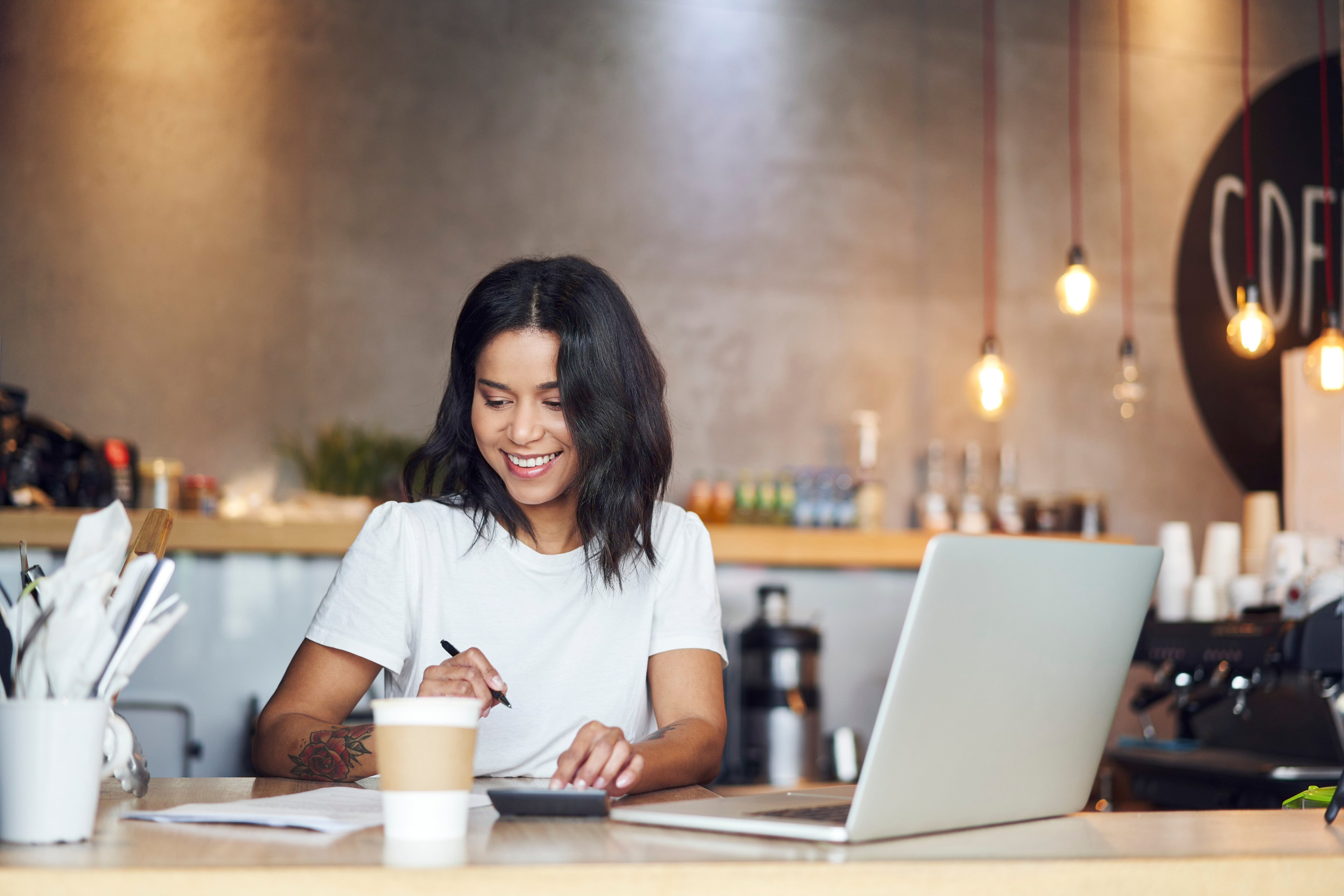 Woman in a coffee shop with papers and a laptop